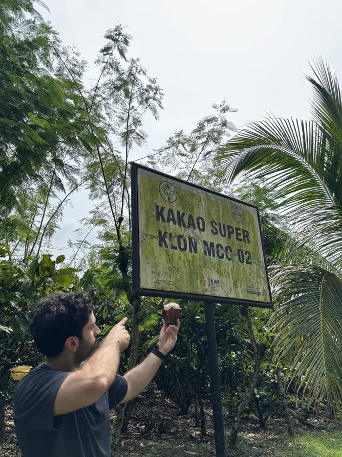 Ali pointing at the KAKAO SUPER KLON MCC 02 sign in an ICCRI research plot